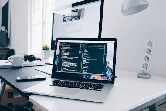 Laptop displaying a code editor on a desk, representing custom software development